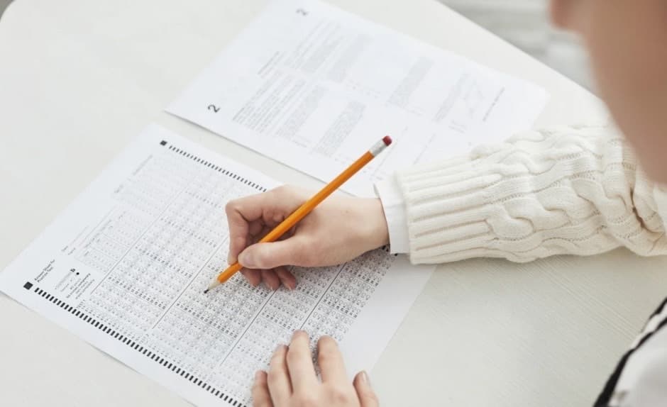A woman sitting at a desk, smiling at her laptop.